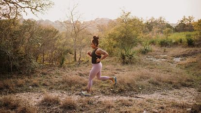 A woman runs solo along a trail.