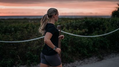 A woman runs alongside a rising sun.