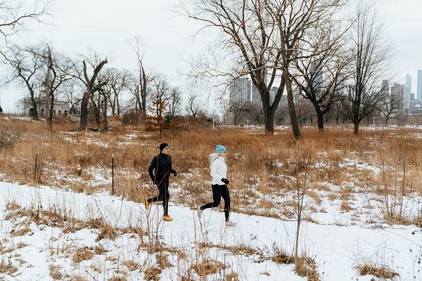 Two runners run in the snow.